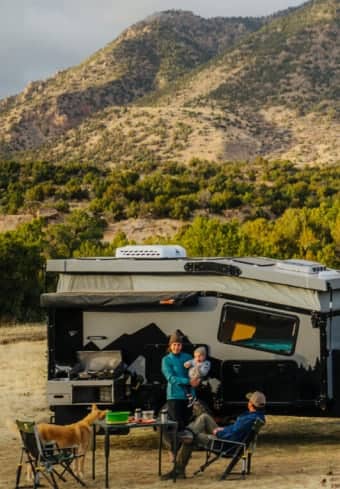 Famiglia che si rilassa accanto al proprio camper in montagna