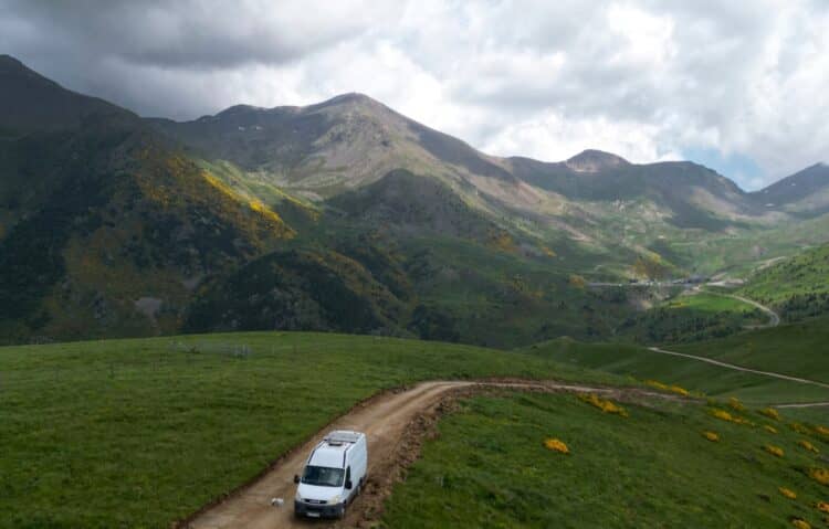 Camper furgonato su una strada sterrata tra montagne verdi