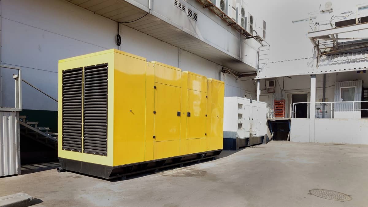 Un grande generatore giallo posizionato in un piazzale industriale