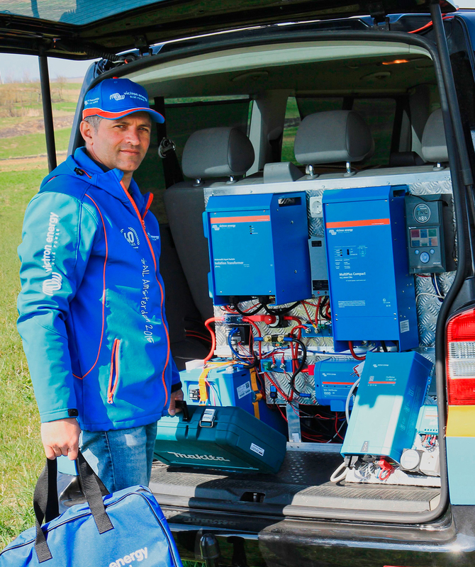 Professionista di Victron in piedi accanto a un dispositivo Victron nella parte posteriore di un’automobile